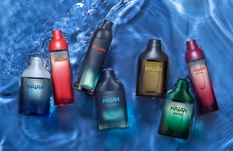 Foto de siete frascos de perfume Kaiak de diferentes colores (azul, rojo, verde y gris) dispuestos sobre una superficie azul que simula agua en movimiento.